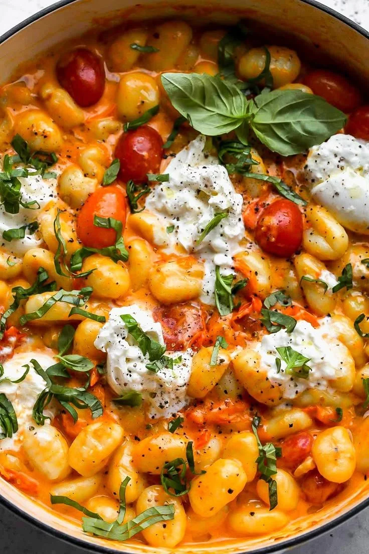 Plate of creamy tomato gnocchi topped with burrata cheese and fresh basil