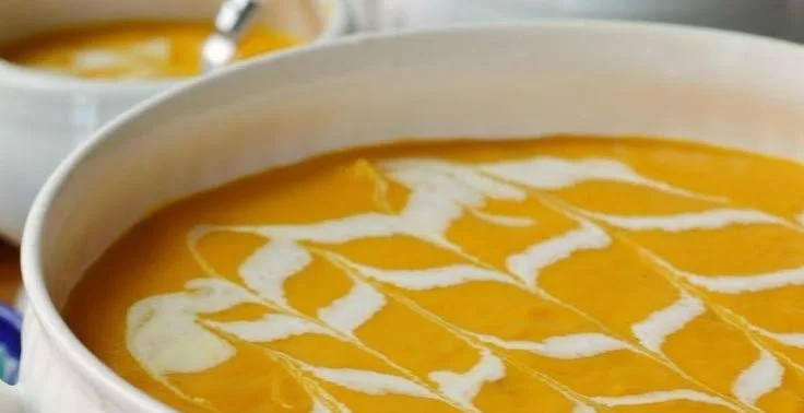Bowl of carrot apple soup topped with herbs