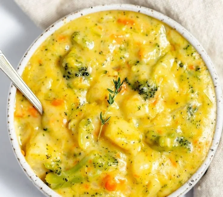 Delicious cheesy broccoli potato soup in a rustic bowl garnished with herbs