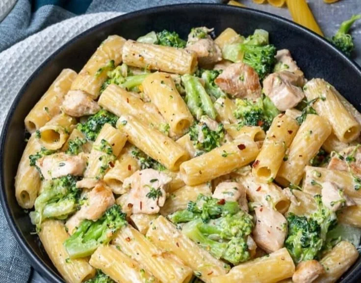 A delicious plate of chicken broccoli pasta garnished with herbs.