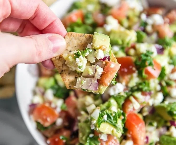 Creamy avocado feta dip served in a bowl with fresh herbs and crackers