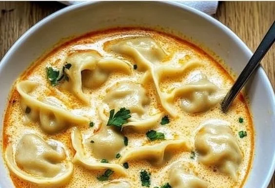 Bowl of creamy Thai dumpling soup garnished with fresh herbs and spices