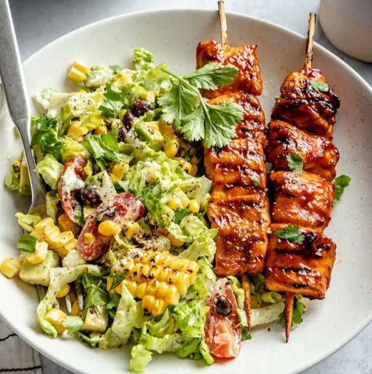 Grilled BBQ chicken skewer salad topped with fresh vegetables.