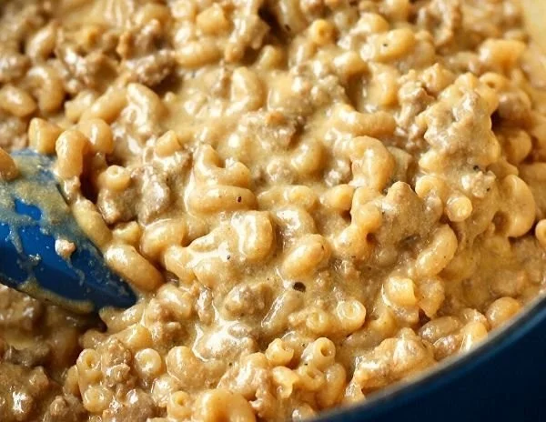 A bowl of homemade Hamburger Helper topped with cheese and herbs.