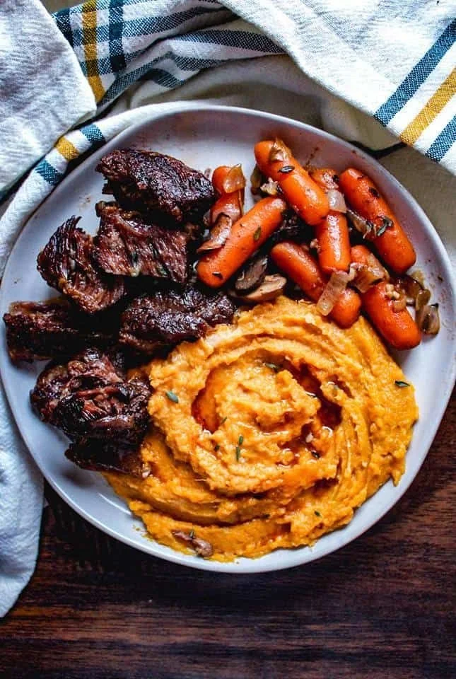 Super tender crockpot beef short ribs served with vegetables and sauce